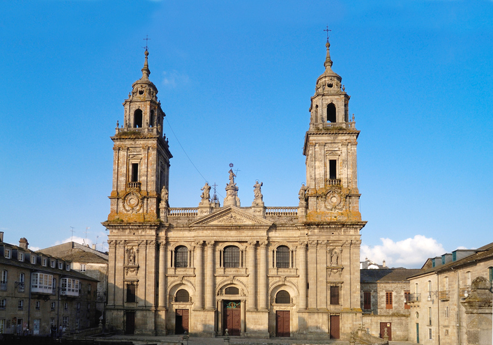 Die imposante Front der Kathedrale von Lugo mit zwei hohen Barocktürmen und einer detailreichen Fassade unter blauem Himmel.