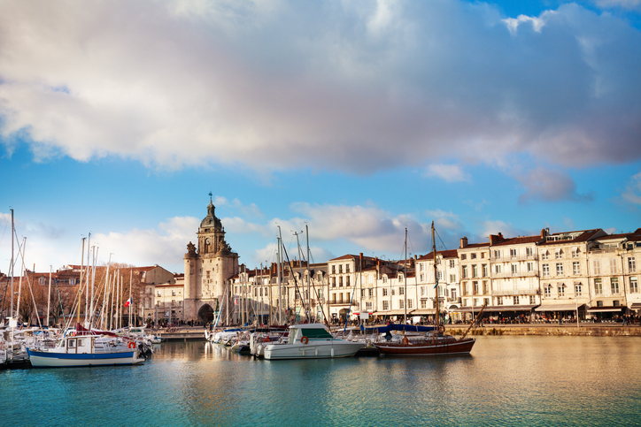 Blick über das Hafenbecken mit vielen Segelbooten auf die Skyline von La Rochelle und den markanten Uhrturm.