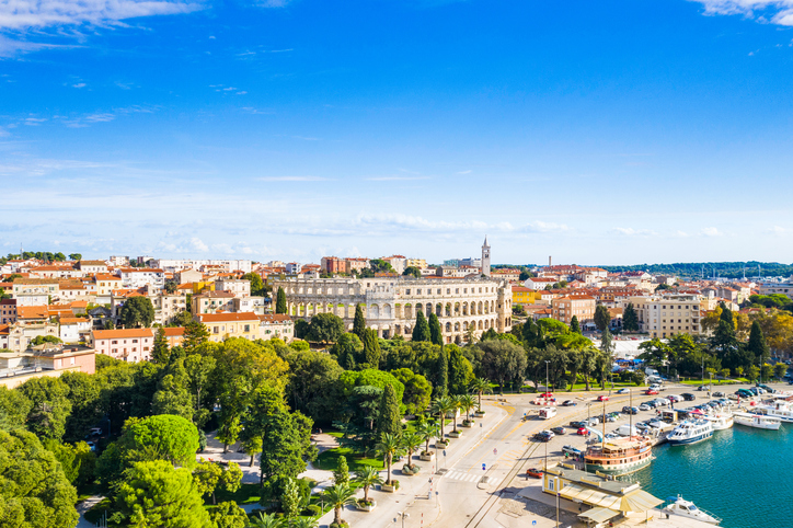 Panoramablick über die Stadt Pula mit dem römischen Amphitheater im Zentrum und dem angrenzenden Hafenbecken.
