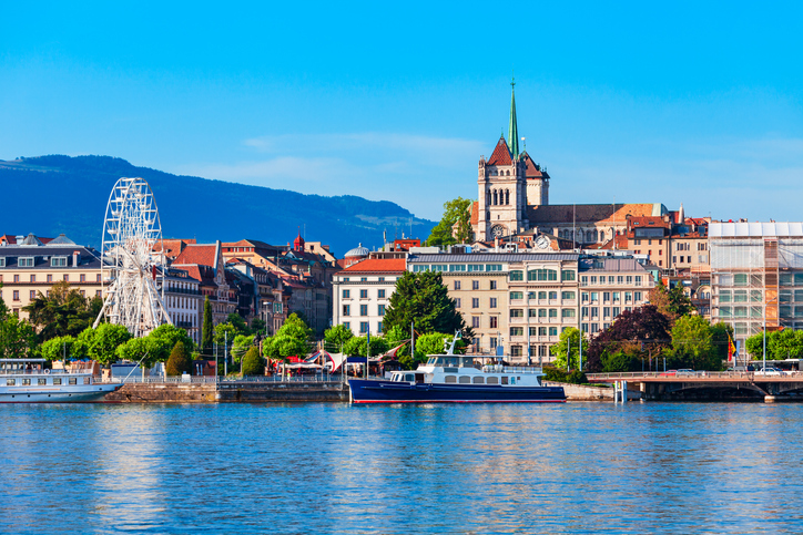 Am Wasser stehen Gebäude, ein Riesenrad und ein markanter Kirchturm.