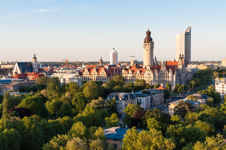 Ein Panoramablick über das grüne Leipzig mit historischen Gebäuden, Kirchen und dem modernen City-Hochhaus im Hintergrund.
