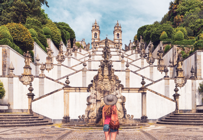 Eine Frau steht vor der barocken Zickzack-Treppe, die zur Wallfahrtskirche Bom Jesus do Monte hinauf führt.