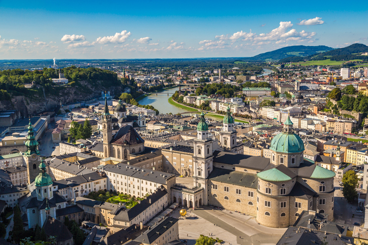 Eine Luftaufnahme zeigt Kirchenkuppeln, Altstadt und den Fluss unter blauem Himmel.
