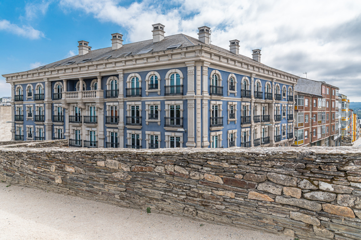 Ein elegantes, blau-grau verziertes historisches Gebäude mit vielen Balkonen direkt hinter der alten Stadtmauer von Lugo.