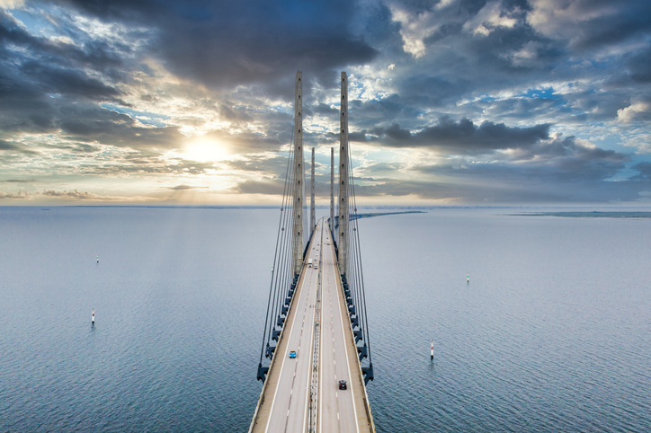 Eine Luftaufnahme der gigantischen Öresundbrücke, die bei tiefstehender Sonne über das Meer in Richtung Horizont führt.