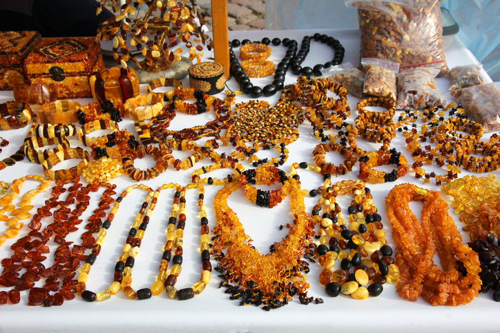 Viele Ketten und Schmuckstücke aus hellem und dunklem Bernstein liegen auf einem Tisch.