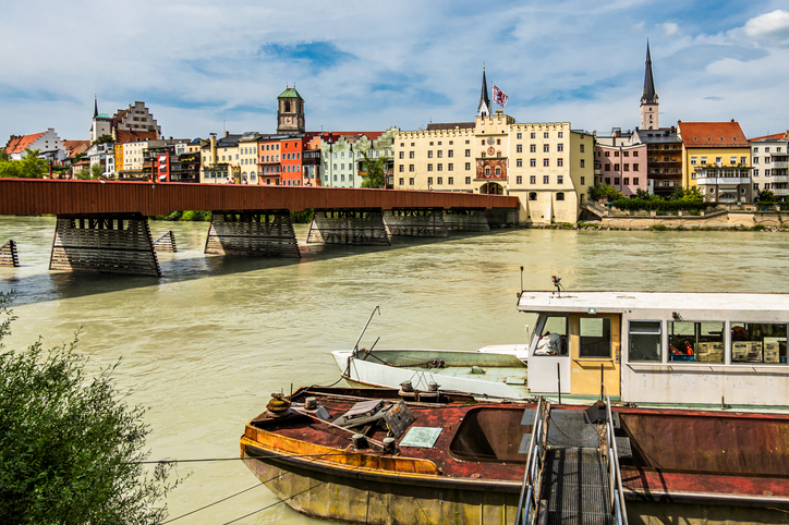 Ein altes Arbeitsschiff im Vordergrund auf dem Inn, dahinter die Silhouette der Rosenheimer Altstadt.