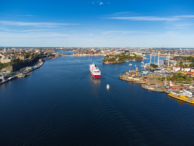 Ein großes Fährschiff fährt durch die weiten blauen Wasserwege zwischen den bewaldeten Inseln des Stockholmer Schärengartens.