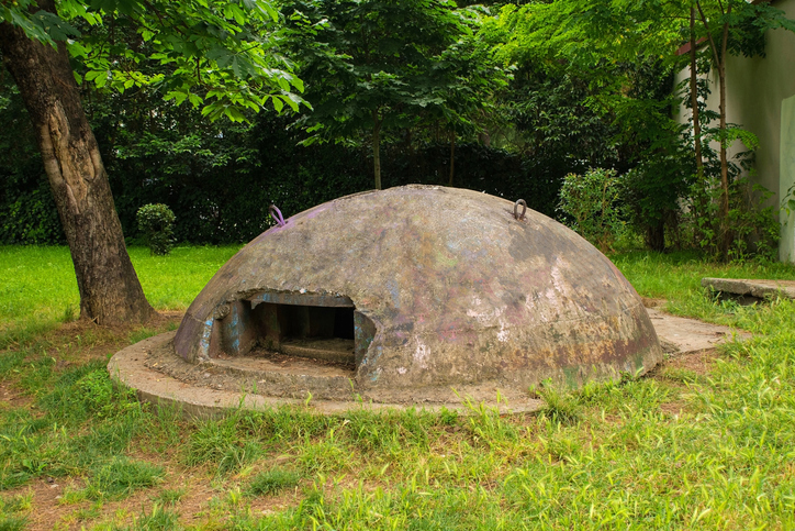 Ein kleiner, kuppelförmiger Betonbunker aus der Zeit des Kommunismus in einer Parkanlage.