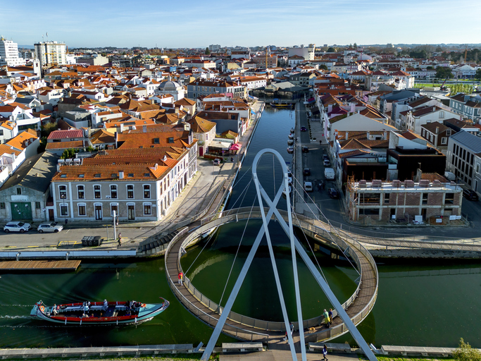 Luftaufnahme der weißen Fußgängerbrücke und des Kanals inmitten der roten Dächer von Aveiro.