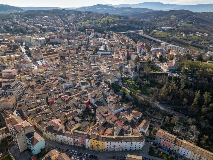 Weite Luftaufnahme des dichten historischen Stadtzentrums mit vielen Dächern und umliegenden Hügeln.
