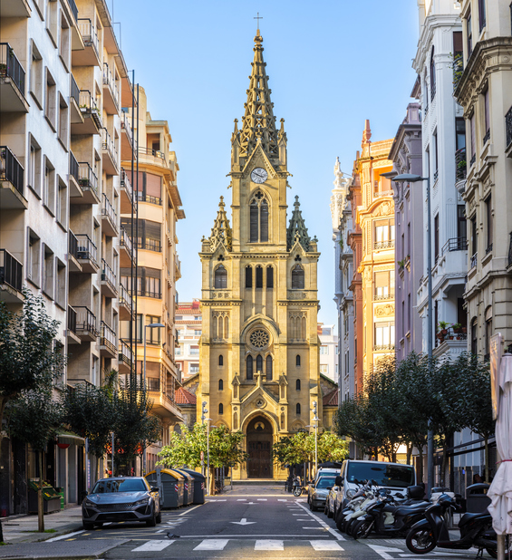 Eine Kirche steht am Ende einer geraden Straße zwischen hohen Wohnhäusern.