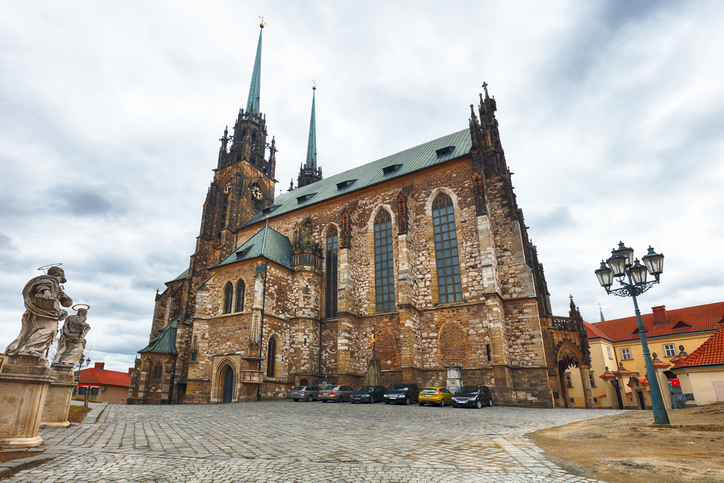 Eine mächtige Kirche mit zwei spitzen Türmen steht auf einem gepflasterten Platz.