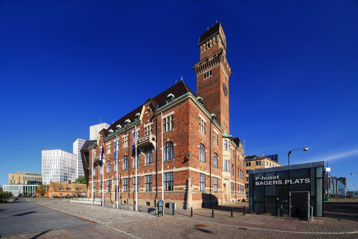 Ein prachtvolles Backsteingebäude mit einem hohen Turm und aufwendigen Verzierungen an einem sonnigen Platz.