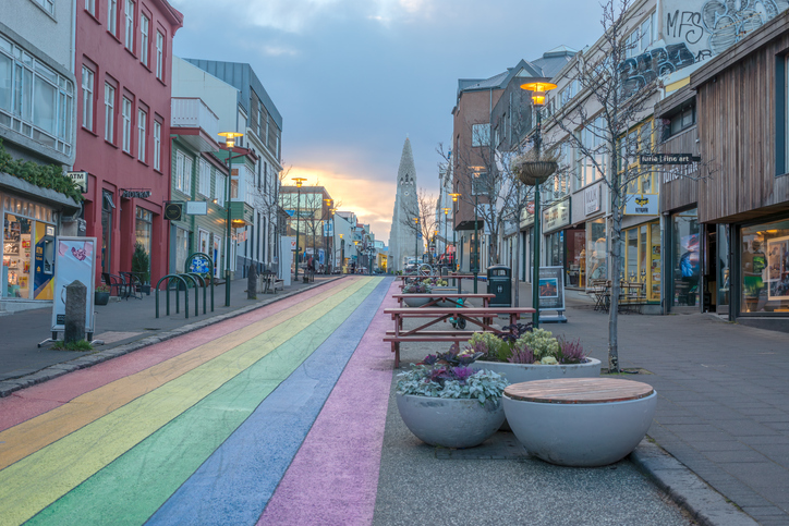 Eine bunt bemalte Straße in Regenbogenfarben führt direkt auf die imposante Hallgrímskirkja in Reykjavík zu.
