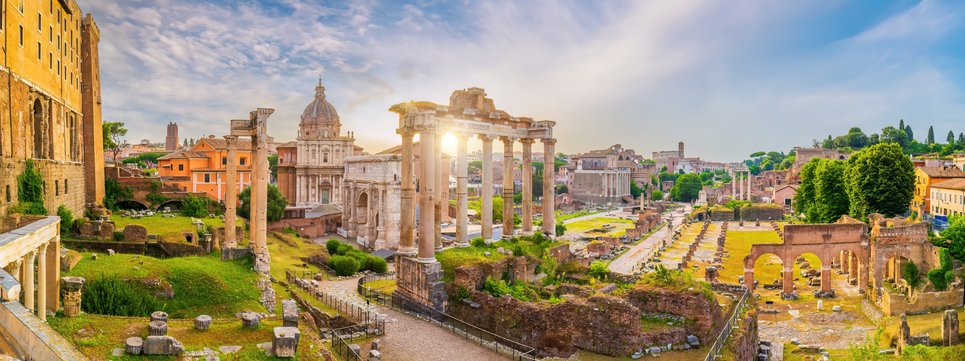 Weitläufiger Blick über die Ruinen des Forum Romanum mit antiken Säulen, Bögen und Kirchen im warmen Licht der Abendsonne.