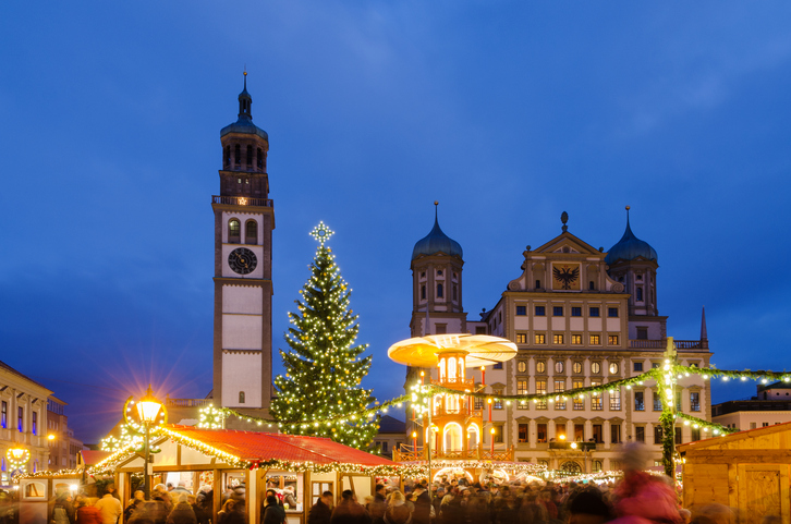 Festlich beleuchteter Weihnachtsmarkt auf dem Rathausplatz in Augsburg mit großem Weihnachtsbaum und Pyramide.