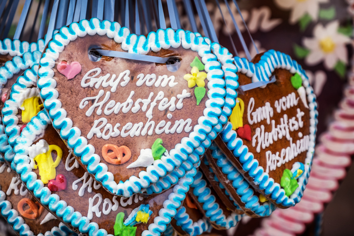 Mehrere Lebkuchenherzen mit der Aufschrift „Gruß vom Herbstfest Rosenheim“ an einem Marktstand.