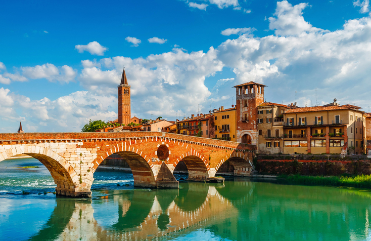 Die historische römische Bogenbrücke Ponte Pietra aus rotem Backstein und weißem Stein über dem Fluss Etsch in Verona.