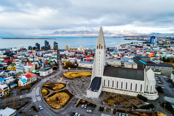 Eine Drohnenaufnahme zeigt die Hallgrímskirkja inmitten des Stadtzentrums von Reykjavík mit Blick auf den Hafen.