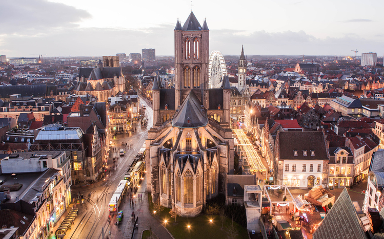 Luftaufnahme von Gent mit der St.-Nikolaus-Kirche und einem Riesenrad bei Nacht.