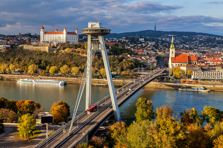 Eine große Brücke mit markanter Aussichtsplattform spannt sich über den Fluss vor der Stadt.