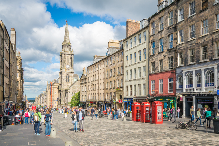 Belebte Royal Mile in Edinburgh mit historischen Gebäuden, Menschen und roten Telefonzellen