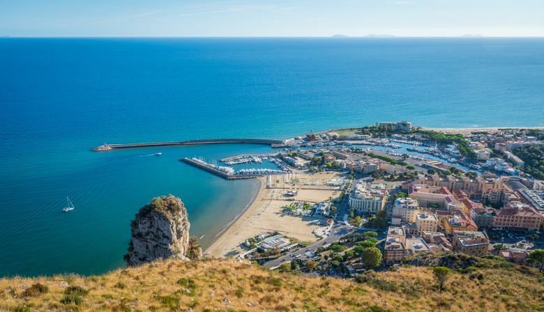 Blick von einer Anhöhe auf das tiefblaue Meer, den Hafen von Terracina und die modernen Viertel am Strand.