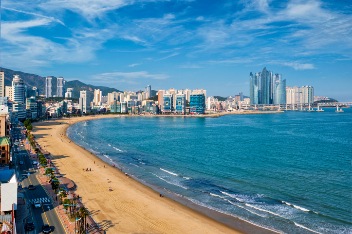 Der Haeundae Strand in Busan mit hellem Sand, blauem Meer und einer imposanten Skyline im Hintergrund.