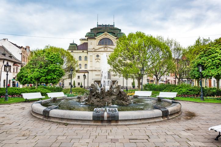 Frontansicht des Staatstheaters in Košice mit einem großen Springbrunnen und gepflegten Grünanlagen im Vordergrund.