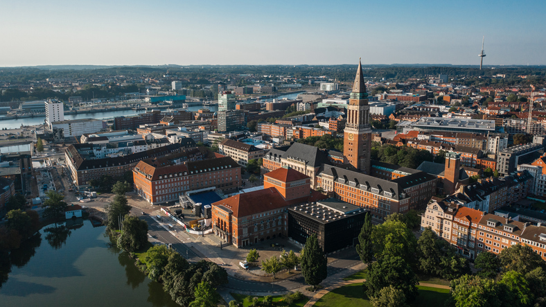 Weite Luftaufnahme von Kiel mit Rathaus, Innenstadt, Hafenbereich und Blick über die Förde.