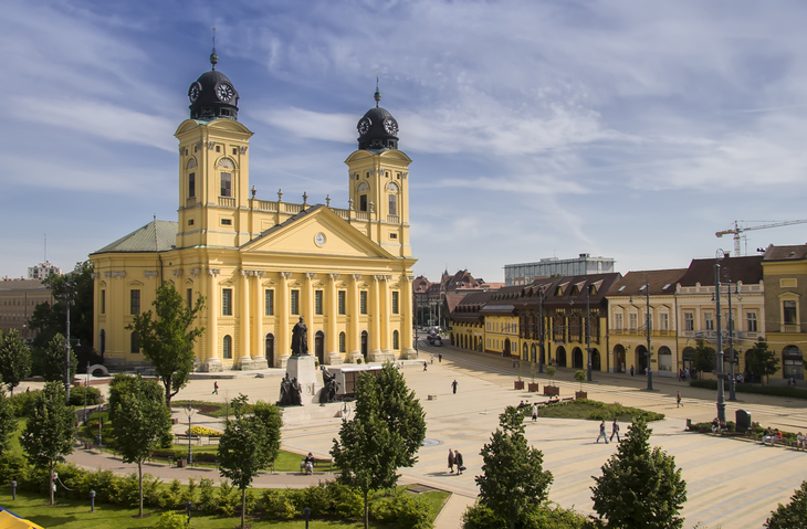Blick auf die imposante gelbe Fassade der reformierten Großkirche auf dem Hauptplatz von Debrecen