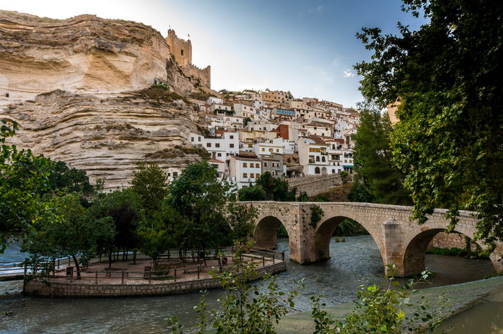 Eine historische Steinbrücke führt über den Fluss zu einem Dorf auf einem Felsen in Albacete
