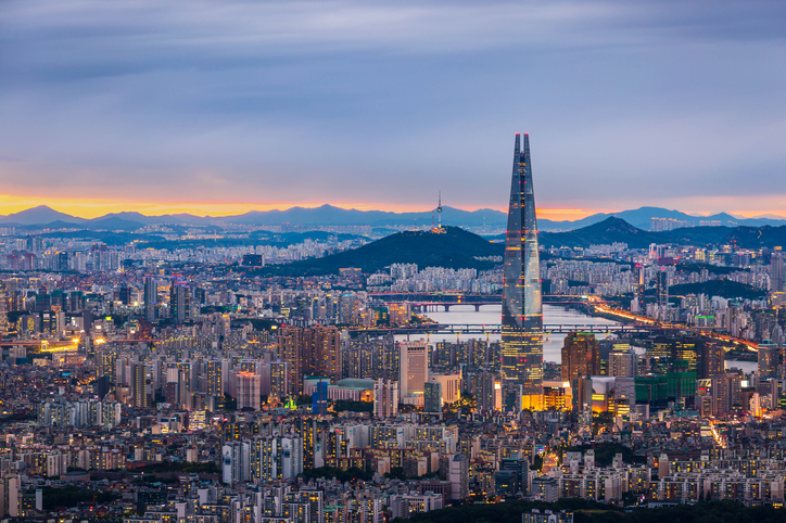 Eine nächtliche Luftaufnahme von Seoul mit dem beleuchteten Lotte World Tower, der weit über die Stadt ragt.