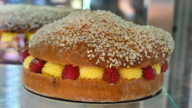 Eine frisch zubereitete Tarte Tropézienne mit Vanillecreme und frischen Himbeeren in einer Auslage