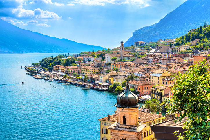 Blick von oben auf die bunten Häuser, die Kirche und den Hafen von Limone direkt am Ufer des Gardasees.