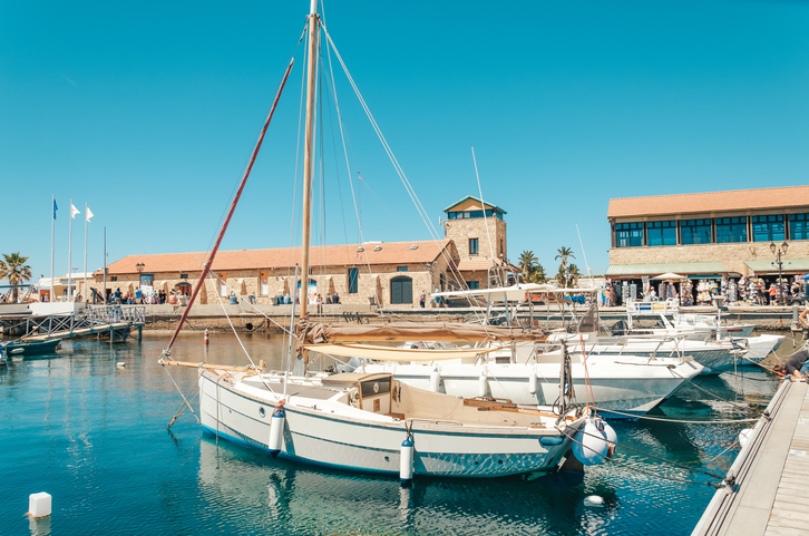 Ein hölzernes Segelboot liegt neben modernen Jachten im ruhigen Hafenbecken von Paphos.