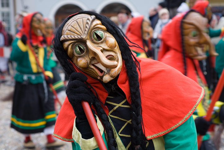 Nahaufnahme einer Person in einem traditionellen Narrenhäs mit einer geschnitzten Holzmaske.