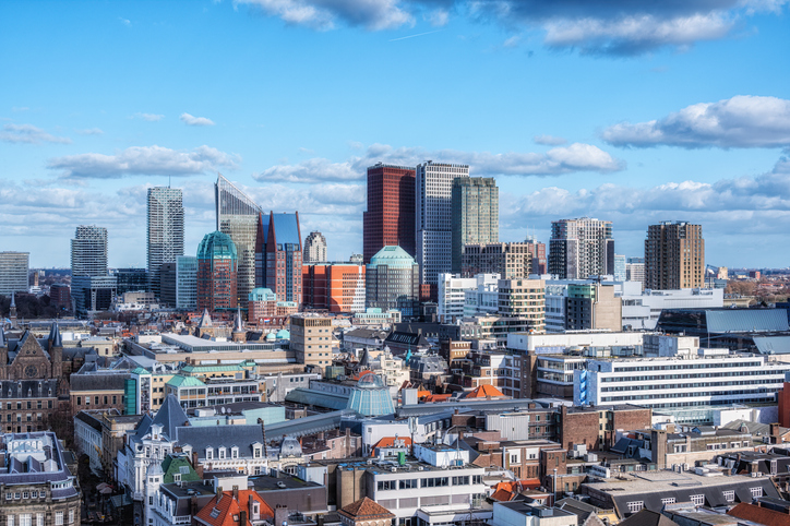 Panorama der Hochhaus-Skyline von Den Haag mit einer Mischung aus moderner Glasarchitektur und historischen Backsteindächern.