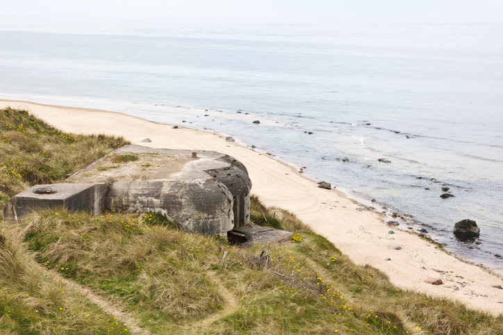 Ein schwerer Betonbunker steht einsam in einer hügeligen Dünenlandschaft am Strand von Hirtshals