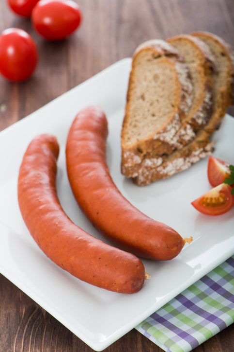 Klassische ungarische Debrecziner Wurst serviert mit frischem Brot und Tomaten