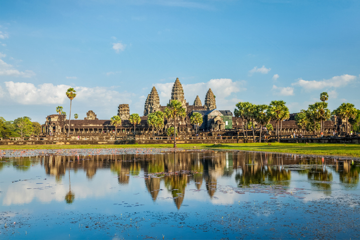 Der Tempel Angkor Wat spiegelt sich malerisch in einem Wasserbecken vor dem Hintergrund eines blauen Himmels