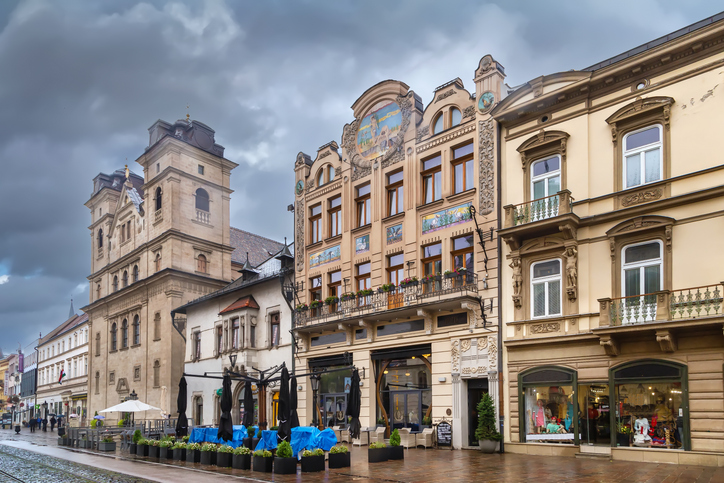 Eine Reihe historischer Gebäude in Košice mit verzierten Fassaden und Malereien unter einem bewölkten Himmel.