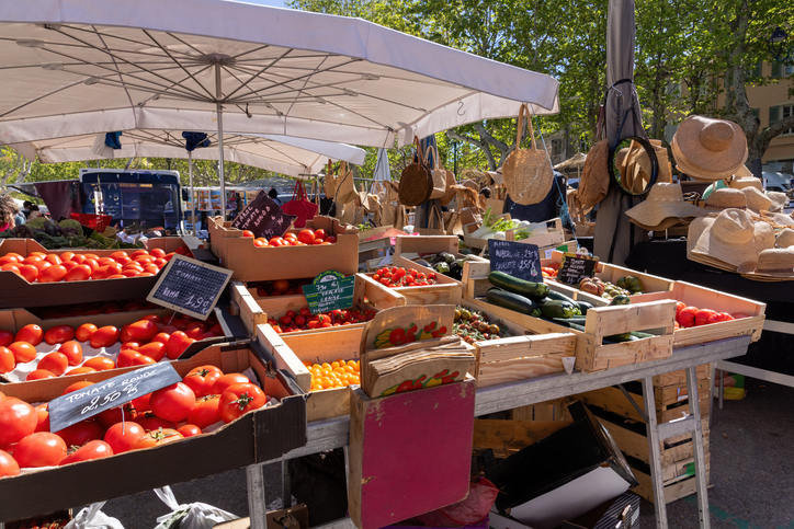 Marktstand mit einer großen Auswahl an frischen Tomaten, Zucchini und Sommerhüten in Saint-Tropez