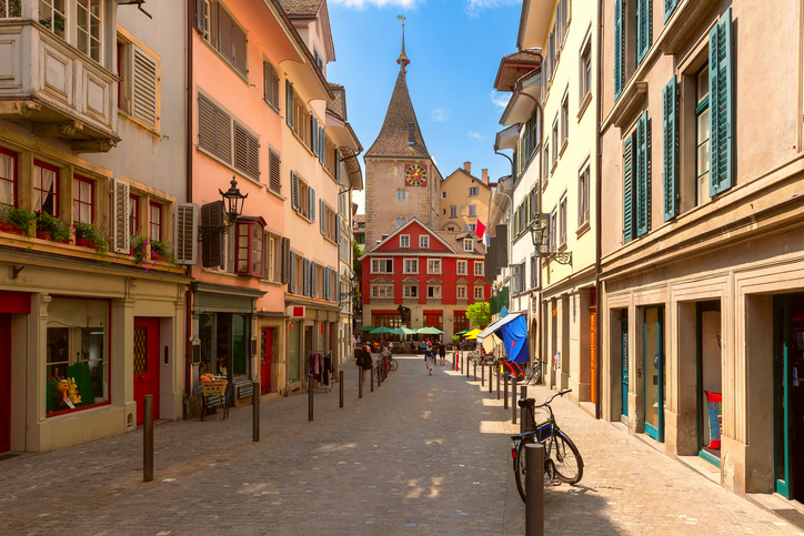 Blick durch eine schmale Pflastersteingasse mit bunten historischen Häusern und Erkern in der Zürcher Altstadt.