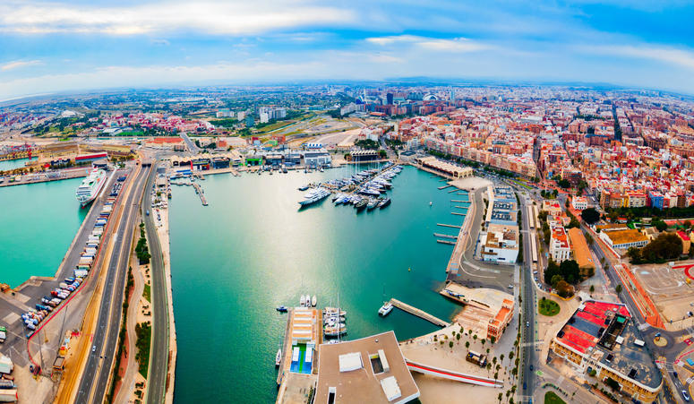 Eine Luftaufnahme des weiten Hafenbeckens von Valencia mit vielen Yachten und der angrenzenden Stadtstruktur.
