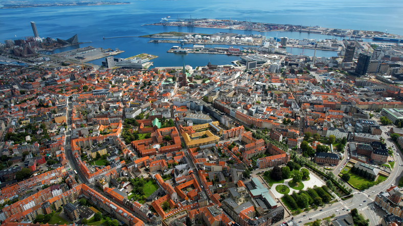 Eine weite Luftaufnahme über das Stadtzentrum von Aarhus bis hin zum modernen Hafen und der Ostsee.