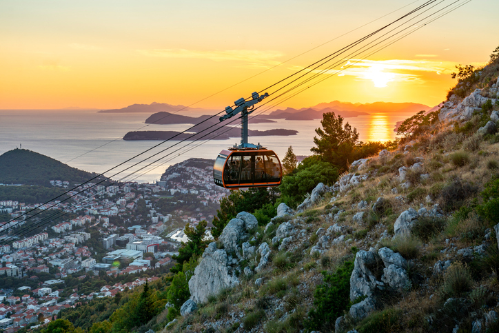 Seilbahn fährt bei Sonnenuntergang über die Küste von Dubrovnik