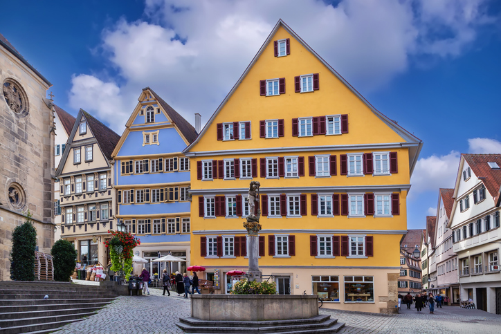 Farbenfrohe Häuser, Kopfsteinpflaster und ein Brunnen in der historischen Innenstadt von Tübingen.