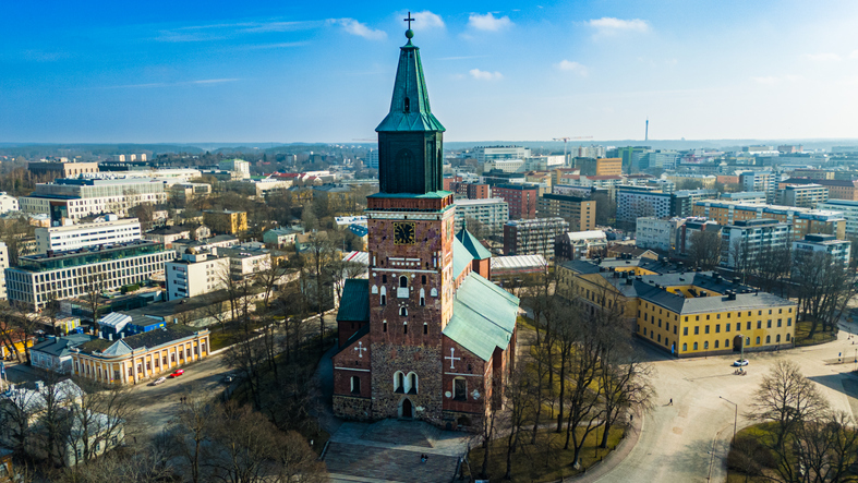 Frontale Luftaufnahme des imposanten Doms von Turku mit seinem grünen Turmhelm inmitten des Stadtzentrums.